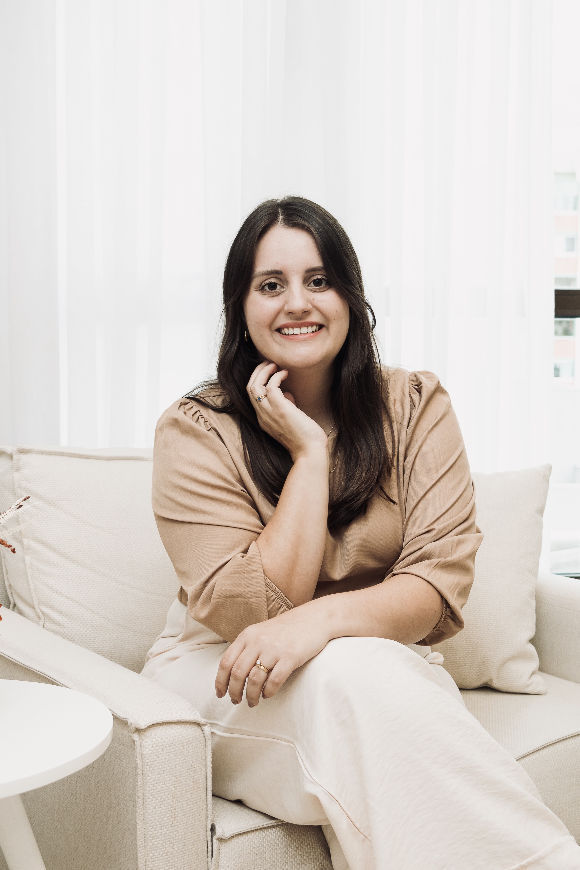 Camila Abreu, psicóloga, sentada no sofá
